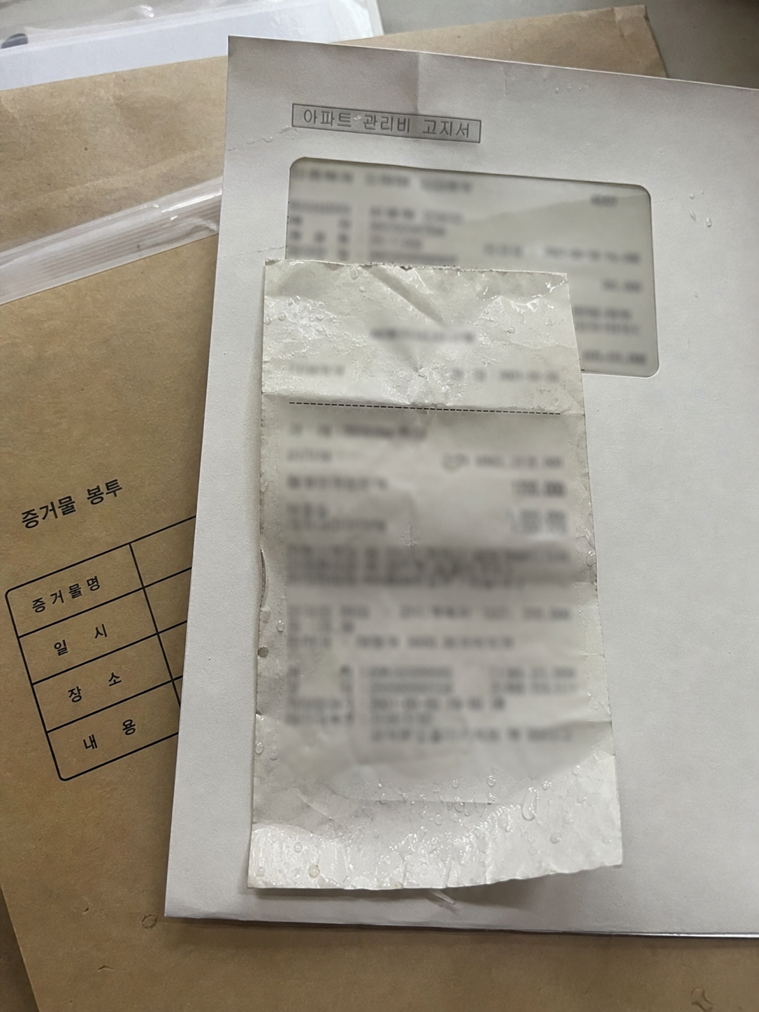 관리비 고지서 위에 놓인 젖은 택시 영수증